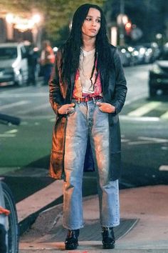 a woman with long black hair is standing on the sidewalk