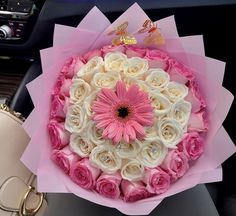 a pink and white flower bouquet sitting on top of a car dashboard