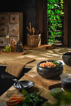 a bowl of food sitting on top of a wooden cutting board next to other foods