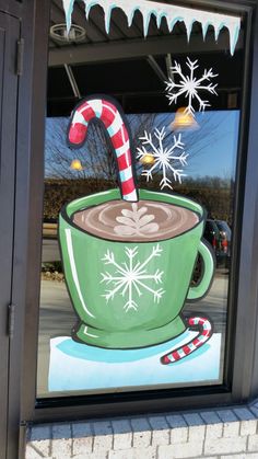 there is a christmas decoration in the window with a cup of coffee and candy cane