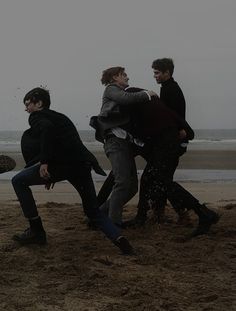 four young men playing frisbee on the beach