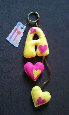 a pair of pink and yellow heart shaped keychains on a black surface next to a tag