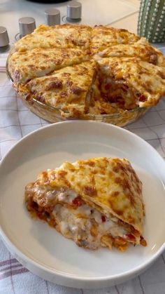 a white plate topped with a cheesy dish next to a casserole