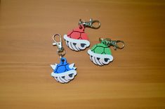 three keychains with different designs on them are sitting on a table together,