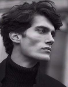 a black and white photo of a man with dark hair wearing a turtle neck sweater