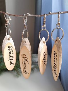 three wooden keychains hanging from a clothes line with personalized tags on them