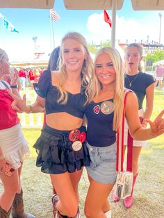 two young women standing next to each other in front of a tent with flags on it