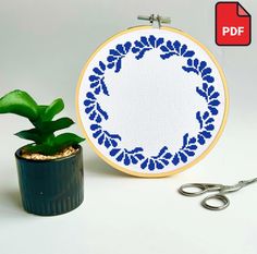 a potted plant sitting next to a cross stitch pattern