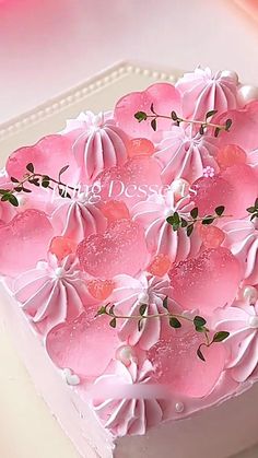 a heart shaped cake with pink frosting and flowers on it's side, sitting on a white platter