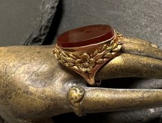 "10k yellow and green gold early 1900s ring-hand wrought, oval bezel set Carnelian(17x10mm), aesthetic design.  Small size 3, wt.- 3.2 grams, 3/4\" north to south on finger.  The ring is yellow gold with green gold hand wrought flowers and leaves sodered to form this elegantly framed stone-photos show details.  Condition is very good any slight wear is commensurate with age.  Earthy color in artist designed ring." Oval Antique Signet Ring As Gift, Antique Hallmarked Oval Cabochon Rings, Antique Oval Signet Ring For Gift, Antique Oval Hallmarked Ring, Antique Oval Collectible Rings, Antique Yellow Gold Oval Cabochon Ring, Vintage Gold Carved Ring, Vintage Gold Carved Signet Ring, Vintage Oval Cameo Ring