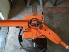 an orange machine is sitting on top of a piece of metal in the process of being used