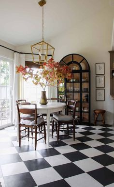 a dining room with black and white checkered flooring, chandelier and table