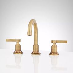 two brass faucets on a white surface