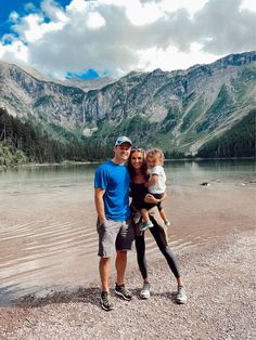 a man, woman and child standing in front of a mountain lake