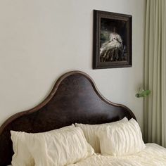 a bed with white pillows and a painting on the wall