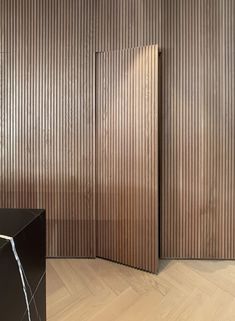 an empty room with wooden slats on the walls and wood flooring in front of it