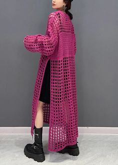 a woman standing in front of a gray wall wearing a pink crochet cardigan