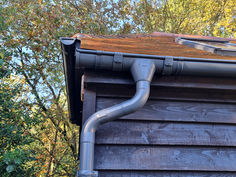 a gutter hose is attached to the roof of a house with trees in the background