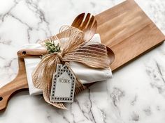 a wooden spatula with a bow on it next to two napkins and a knife