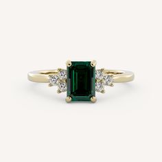 an emerald and diamond ring on a white background