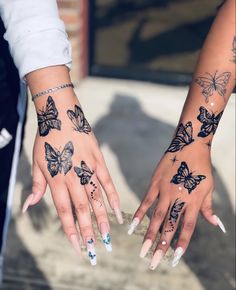 two women's hands with butterfly tattoos on them