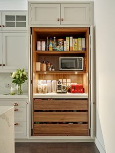 an open cabinet in the middle of a kitchen with lots of items on top of it