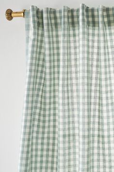 green and white checkered curtains hanging on the side of a window with gold hardware