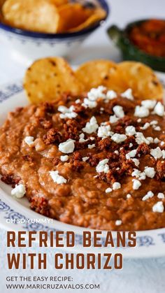 a bowl of refried beans with chorizo and tortilla chips on the side