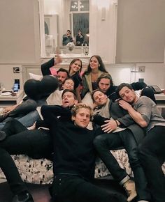 a group of people sitting on top of a bed in a room with white walls