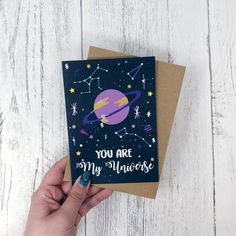 a hand holding up a card with the words you are my universe on it and an image of saturn