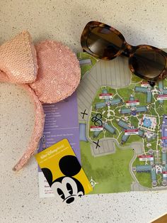 a minnie mouse hat, sunglasses and map on a table