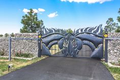 a gate with two horses painted on it's sides and the entrance to a driveway