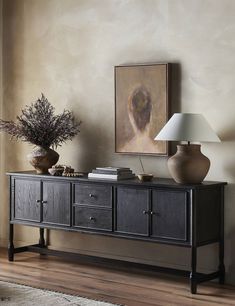 a table with two vases and a painting on the wall behind it in a living room