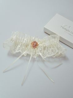 a white garter with a flower on it next to a box