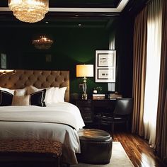 a bedroom with green walls and white bedding, chandelier above the bed