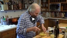 an older man is mixing food in a bowl on the kitchen counter with bottles and utensils