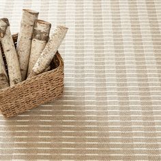 a basket filled with logs sitting on top of a floor next to a white rug