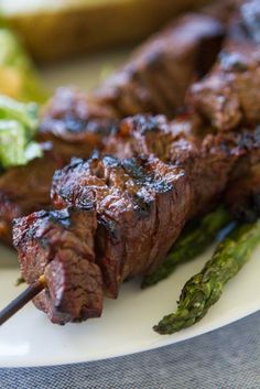 a close up of a plate of food with meat and asparagus on it