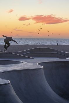 a skateboarder is doing tricks in the air at a skate park near the ocean