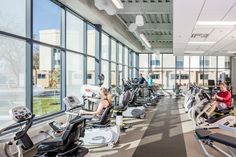 there are many exercise machines in this large room with people working out on the treadmills