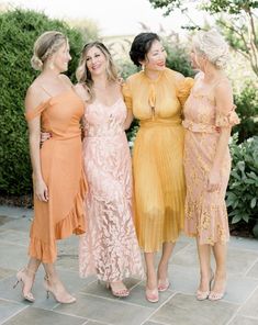 three women in dresses standing next to each other and smiling at the same person's face