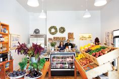 a man and woman standing in front of a counter filled with fruits and vegetables