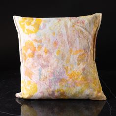 a yellow and pink pillow sitting on top of a table