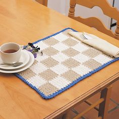 a table with a place mat, coffee cup and saucer on top of it