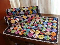 a quilted table top with many different colored buttons on it and a window in the background