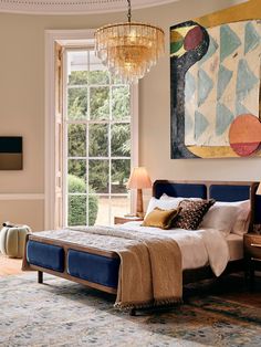 a bedroom with a large painting on the wall and a chandelier hanging from the ceiling