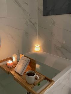 a bath tub with candles and a book on the tray next to it in a bathroom