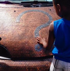 a young boy standing next to the hood of a car with a dollar sign painted on it