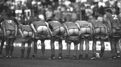 a group of soccer players standing in a line with their backs turned to the side