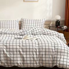 an unmade bed with black and white plaid sheets